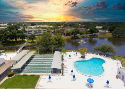 Aerial view of Seminole Gardens pool, shuffleboard courts, and lake at sunset