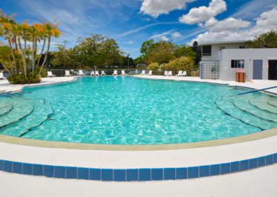 Outdoor swimming pool with lounge chairs and palm trees at Seminole Gardens